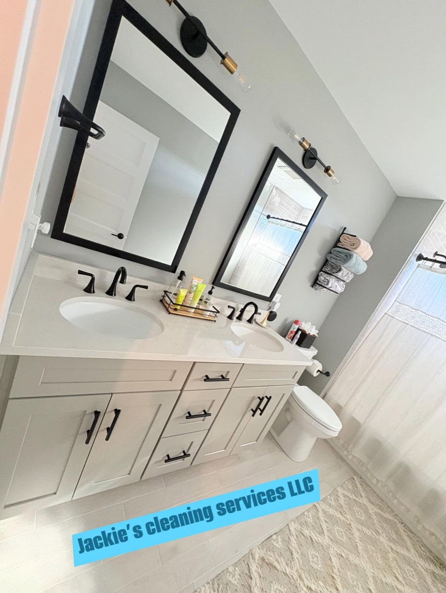 A clean bathroom with a double vanity, black framed mirrors and a white toilet