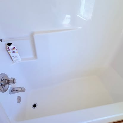A bright white bathtub and shower surround with a clean chrome faucet