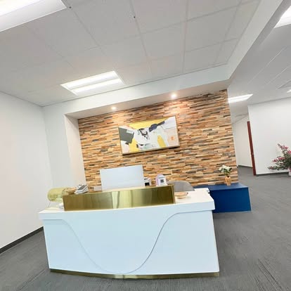 A spotless office lobby with a white and gold reception desk in front of a wood accent wall